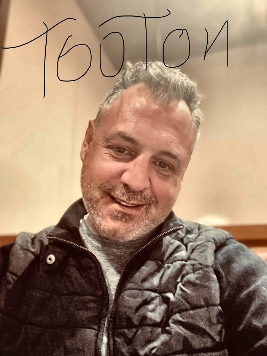 Selfie of Anthony McGrath Tooton IV in a black quilted jacket, with &ldquo;TooTon&rdquo; handwritten across the top